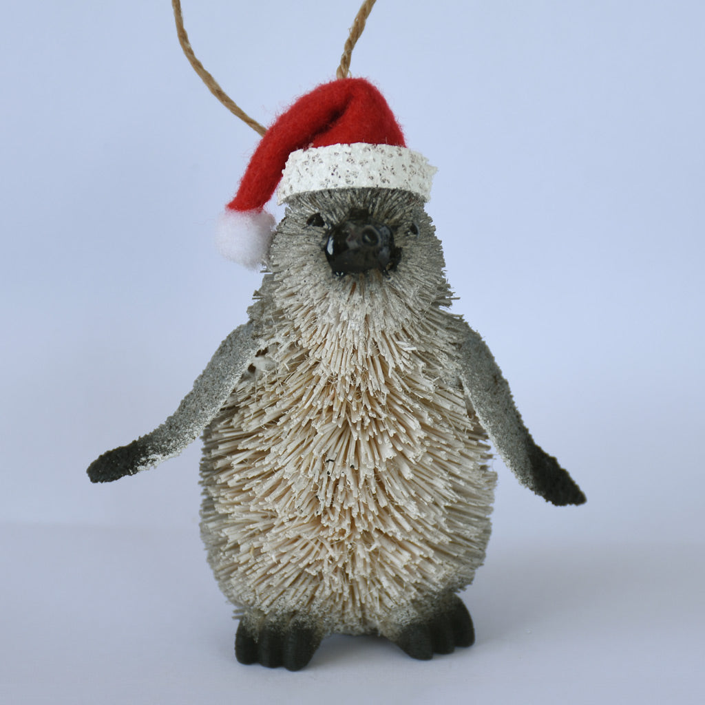 Frontal view of buri fibre Penguin ornament wearing a Santa hat on a white background